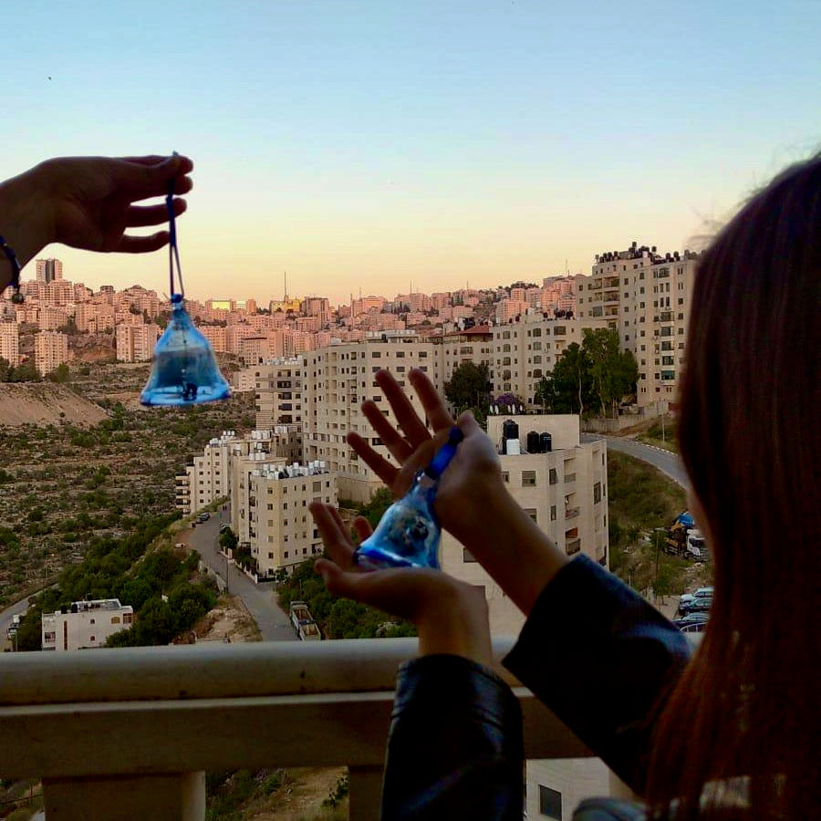 Blue bell Christmas decoration with glass dong in Hebron blue recycled glass. Painted with white snowflake hanging on blue ribbon with Bethlehem town backdrop