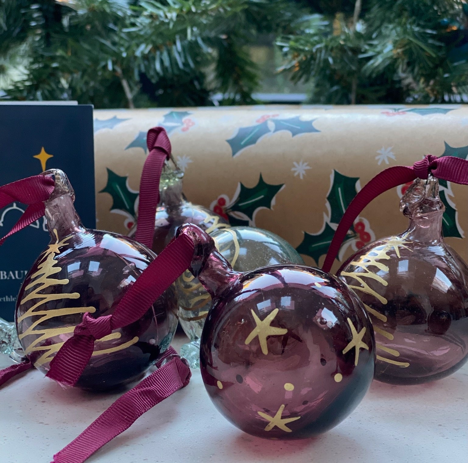 Decorative glass ornaments with star designs on a surface with a Christmas-themed background.
