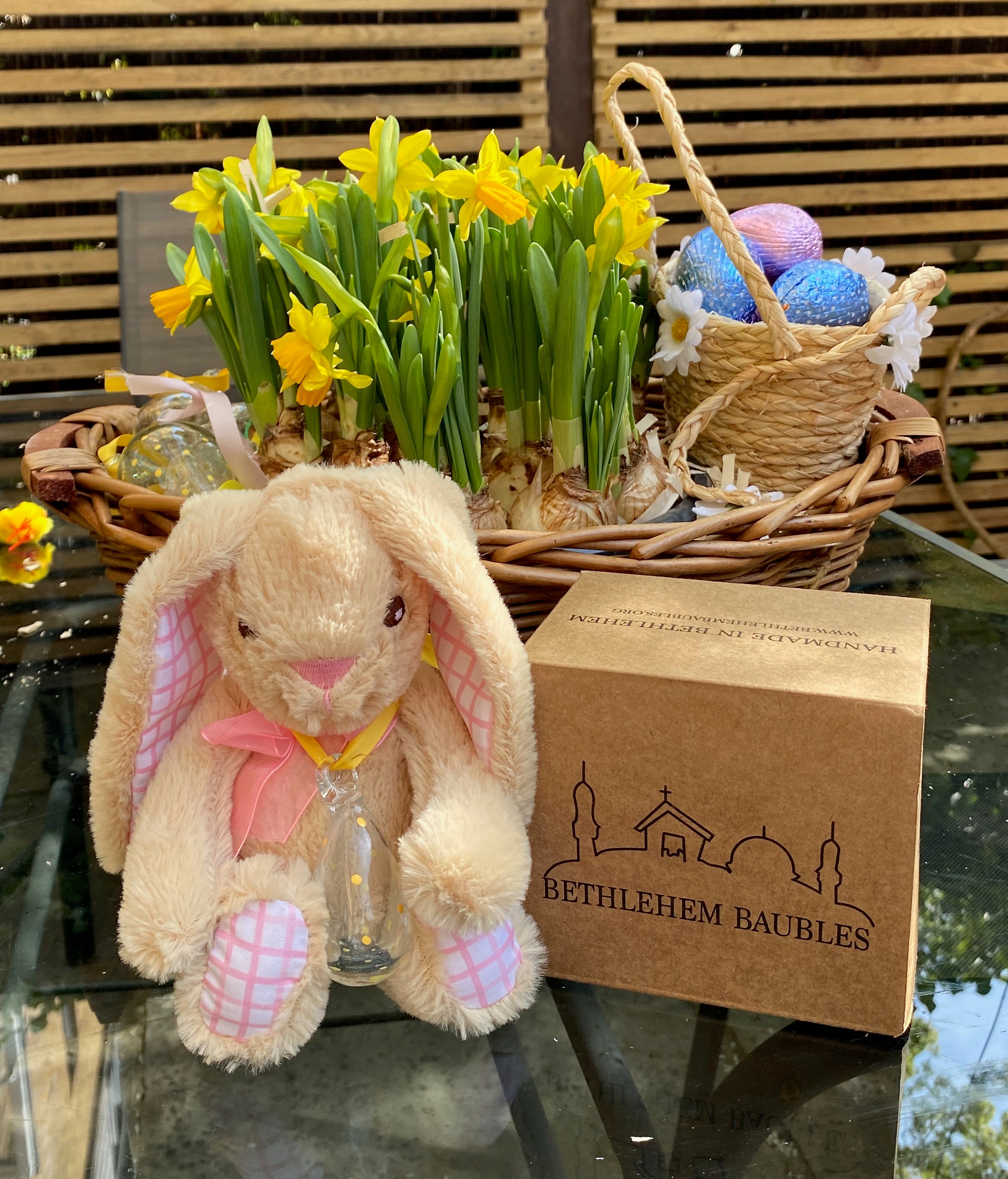 Plush bunny with Easter eggs, daffodils, and a Bethlehem Baubles box on a glass table.
